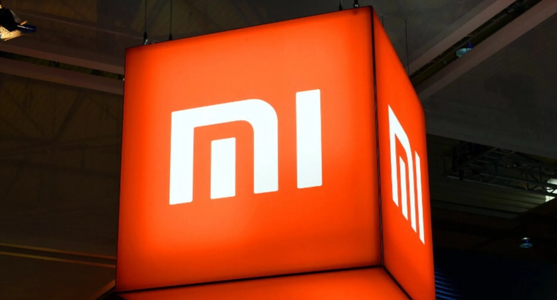 Логотип компанії Xiaomi на яскравому червоному фоні, що символізує інновації в технологіях.